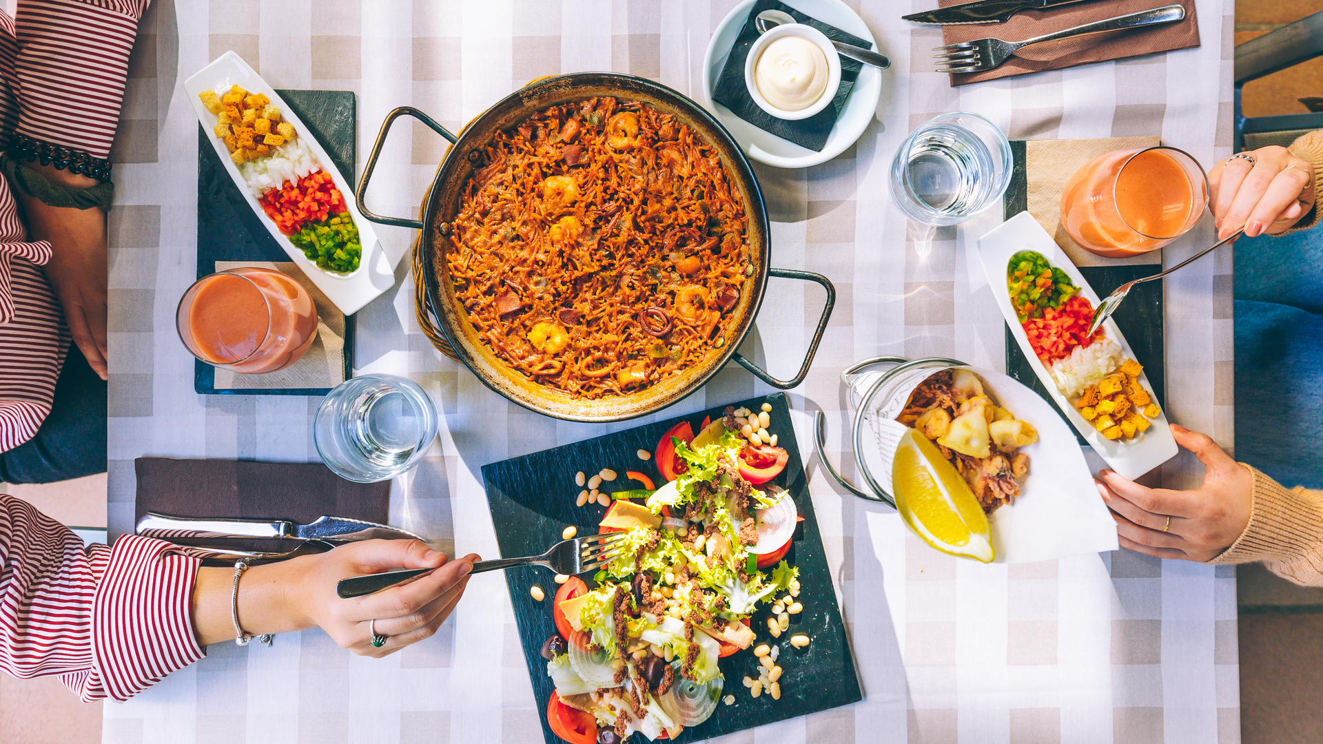 Mesa con paella y ensalada mediterranea